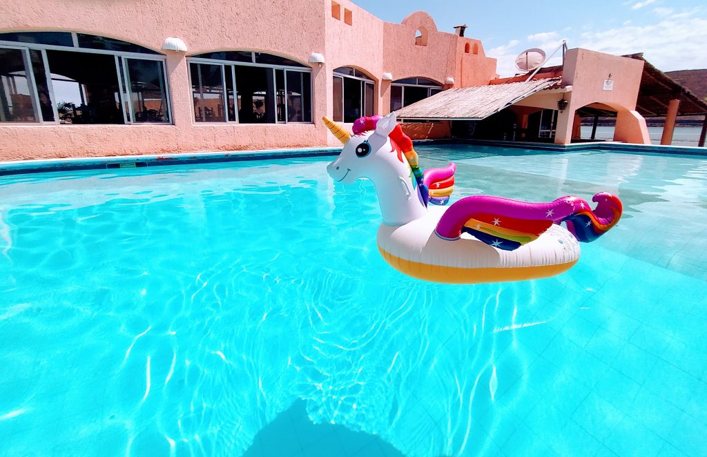 Alberca de Club Hotel Cantamar, hotel de Playa en La Paz, con flotador inflable de Unicornio en las transparentes aguas, La Paz, BCS, México